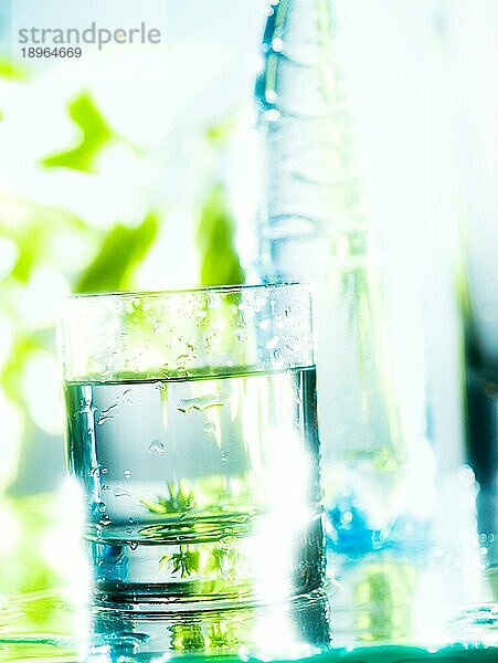 Frisches und kaltes Wasser in einem Glas. Die Transparenz wird durch das Gegenlicht und den Unschärfeeffekt im Hintergrund verstärkt