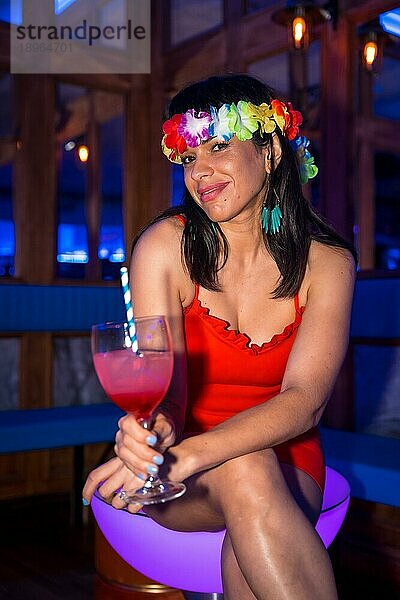 Porträt einer lächelnden lateinamerikanischen Frau mit einem Glas Alkohol  die auf einer Party lächelt