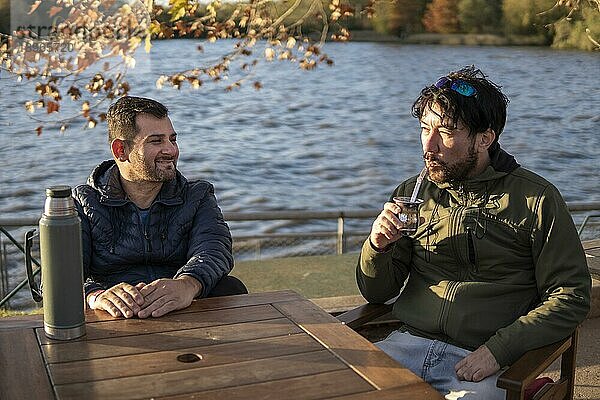 Zwei Freunde genießen den Sonnenuntergang beim Mate trinken