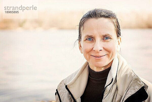 Ein warmes Porträt einer nett lächelnden älteren Frau in der Nähe des Flusses