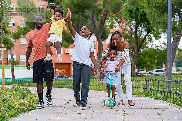 Afrikanische schwarze ethnische Familie mit Kindern auf dem Spielplatz  die Spaß haben und im Stadtpark lächeln