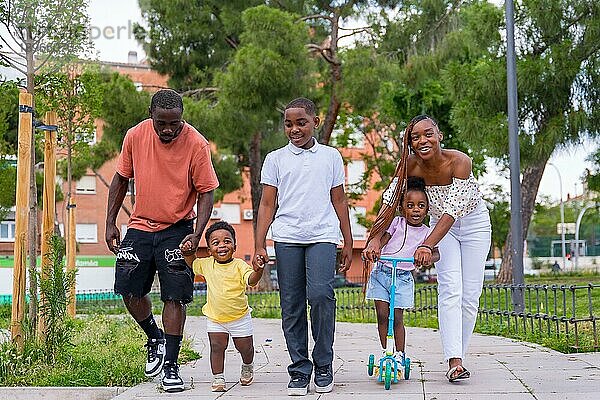 Afrikanische schwarze ethnische Familie mit Kindern auf dem Spielplatz  die Spaß haben und im Stadtpark lächeln