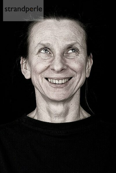 Porträt einer attraktiven erwachsenen Frau  die nach oben schaut und lächelt