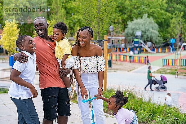 Afrikanische Familie schwarzer Ethnizität  die Spaß mit glücklichen Kindern auf dem Spielplatz hat  die sich nach der Schule gegenseitig begrüßen