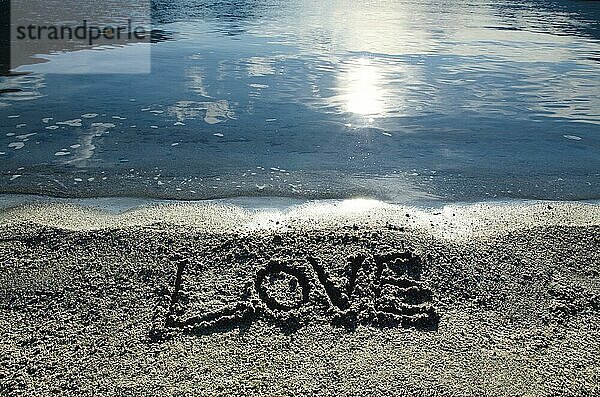 Liebe geschrieben in den Sand Strand in der Nähe des Wassers mit Sonnenlicht
