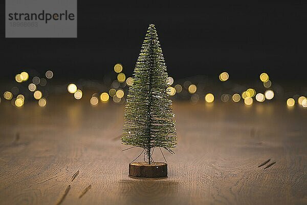 Weihnachtsbaumschmuck auf einer Holzoberfläche mit goldenen Bokeh Lichtern im Hintergrund