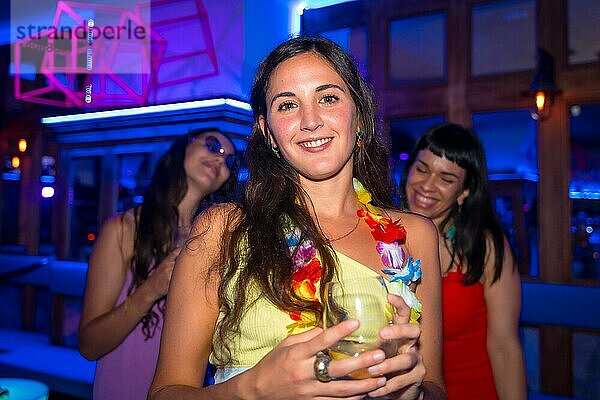 Attraktive Frau lächelnd mit einem Glas Alkohol in einem Nachtclub bei einer Nachtparty