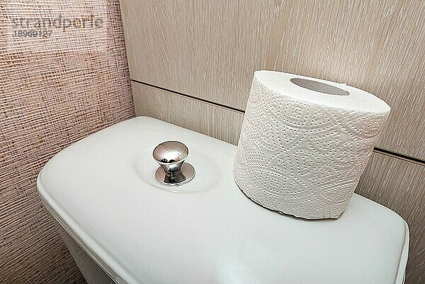 Eine weiche  weiße  hygienische Toilettenpapierrolle wird auf die Spülung in der Toilette gelegt