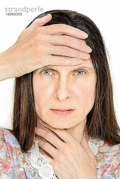Porträt einer Frau mit Kopfschmerzen und Kehlkopfentzündung  wahrscheinlich eine Grippe oder Influenza. Sie hält eine Hand auf den Hals und eine andere auf die Stirn