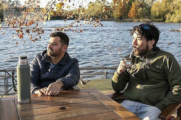 Zwei Freunde genießen den Sonnenuntergang beim Mate trinken