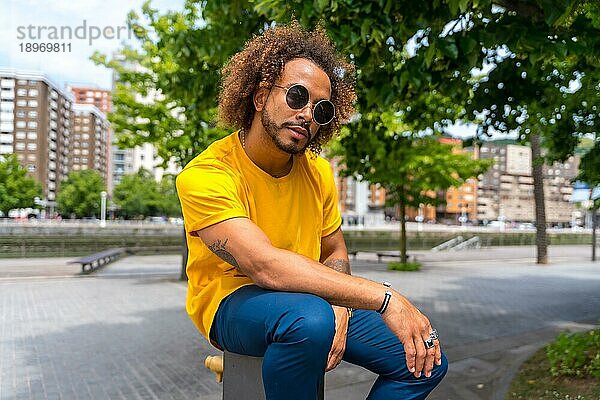 Porträt eines afro haarigen Mannes in einem gelben T Shirt. Porträt in der Stadt lächelnd im Sommerurlaub