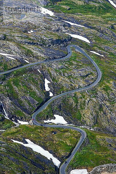 Grüne Landschaft mit Schneeflecken und einer kurvenreichen Straße  gesehen in Norwegen