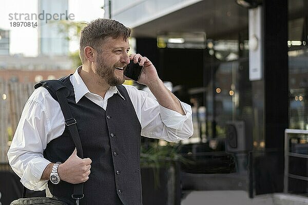 Porträt eines attraktiven Geschäftsmannes  der vor seinem Büro mit einem Freund telefoniert