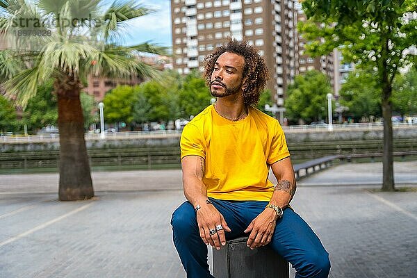 Afrohaariger Mann in gelbem T Shirt. Porträt in der Stadt lächelnd im Sommerurlaub