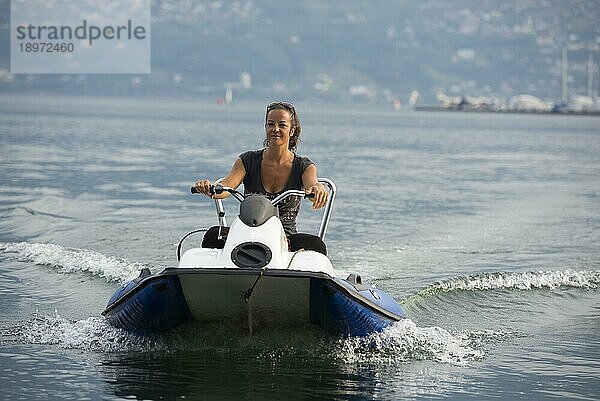 Glückliche Frau  die ein Boot auf dem Wasser fährt