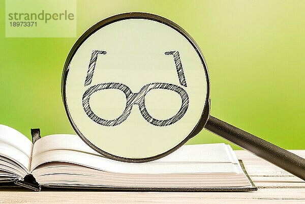 Lesen von Informationen mit einer Bleistiftzeichnung einer Brille in einem Vergrößerungsglas