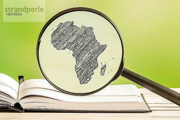Afrika Informationen mit einer Bleistiftzeichnung einer afrikanischen Karte in einem Vergrößerungsglas