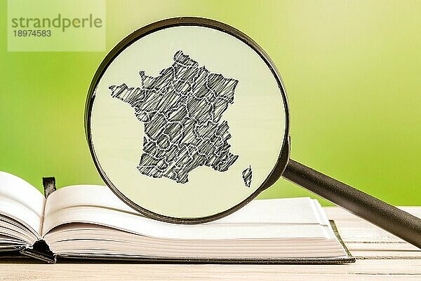 Frankreich mit einer Bleistiftzeichnung einer französischen Landkarte in einem Vergrößerungsglas