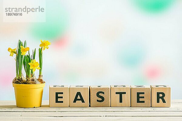 Narzissen in einem Blumentopf auf einem Tisch mit dem Wort Ostern