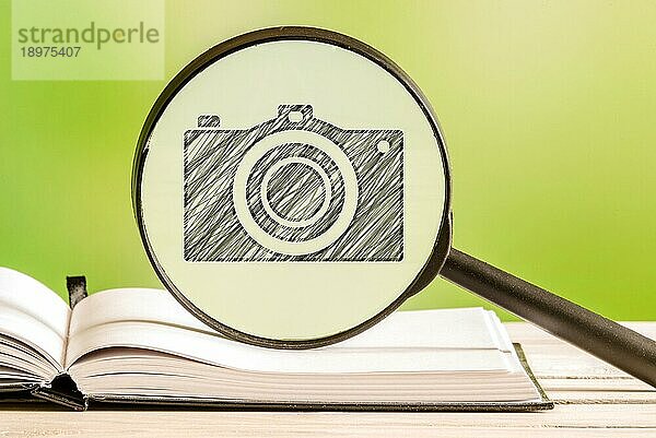 Fotografie Suche mit einer Bleistiftzeichnung einer Kamera in einem Vergrößerungsglas