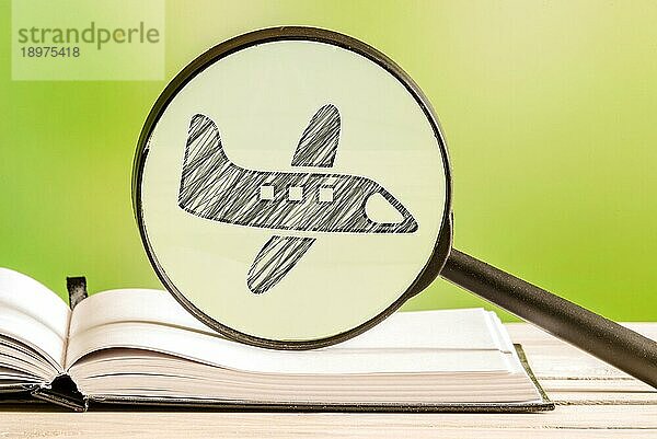 Reiseinformationen mit einer Bleistiftzeichnung eines Flugzeugs in einem Vergrößerungsglas