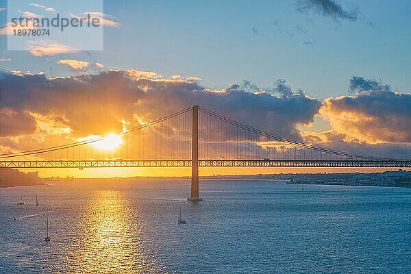 Blick auf die Brücke 25 de Abril  das berühmte touristische Wahrzeichen von Lissabon  die Lisboa und Almada auf der Halbinsel Setubal über den Fluss Tejo mit der Silhouette einer Touristenyacht bei Sonnenuntergang und einem fliegenden Flugzeug. Lissabon  Portugal  Europa