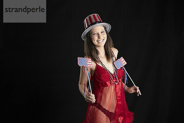 Eine schöne Brünette Modell posiert in einem Studio Umgebung hält Amerika Artikel für den 4. Juli Feier