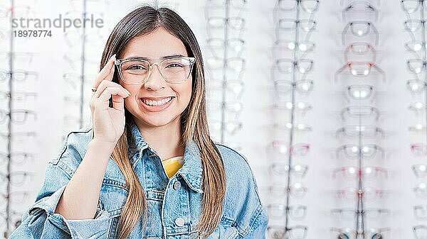 Attraktives Mädchen modelliert eine Brille in einem Brillengeschäft. Porträt einer glücklichen jungen Frau mit Brille in einem Optikgeschäft