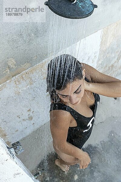 Ein schönes hispanisches brünettes Modell genießt einen Tag im Freien in einer offenen Dusche