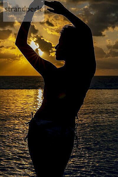 Ein schönes hispanisches Model posiert bei Sonnenaufgang  um den Tag im Urlaub zu beginnen