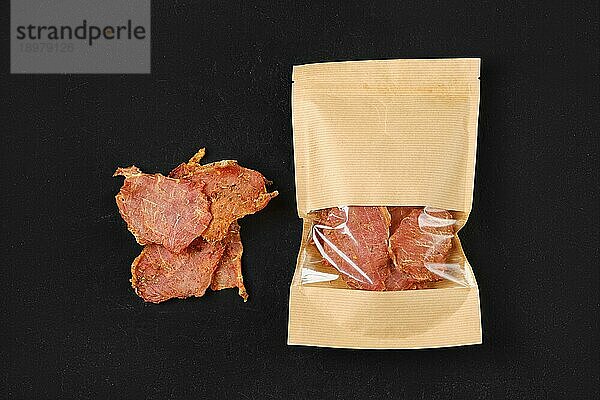 Draufsicht auf pikantes Jerky Schweinefleisch in Papierverpackung