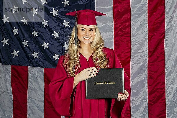 Ein wunderschönes blondes Modell posiert mit einem Diplom mit einer amerikanischen Flagge im Hintergrund