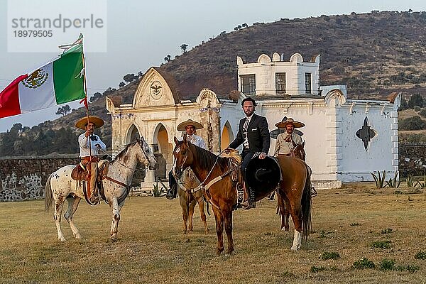 Ein stattlicher mexikanischer Charro posiert vor einer Hazienda in der mexikanischen Landschaft