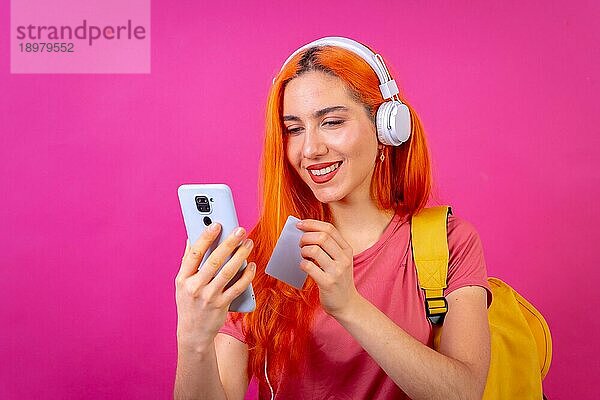 Rothaarige Frau im Studio Fotografie zahlen online mit Handy auf einem rosa Hintergrund