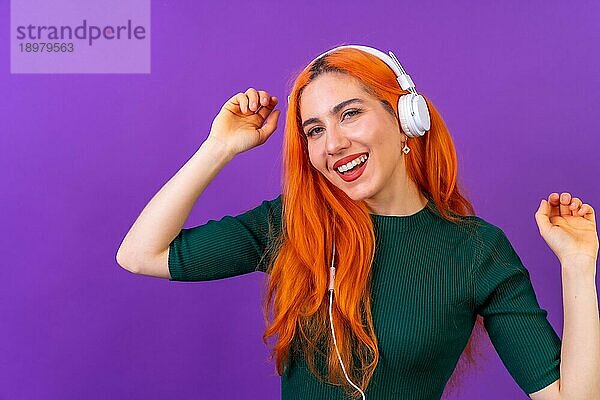 Rothaarige Frau im Studio Fotografie lächelnd tanzen auf einem lila Hintergrund