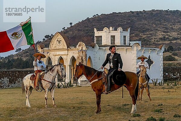 Ein stattlicher mexikanischer Charro posiert vor einer Hazienda in der mexikanischen Landschaft