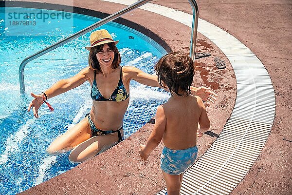 Mutter und Sohn im Pool im Sommerurlaub  Moment der Liebe  der seiner Mutter einen Kuss gibt