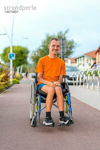 Porträt einer sehr fröhlichen behinderten Person in einem Rollstuhl am Strand im Urlaub
