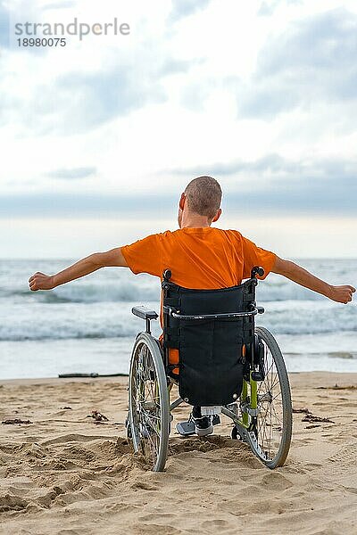 Eine behinderte Person in einem Rollstuhl auf dem Rücken am Strand