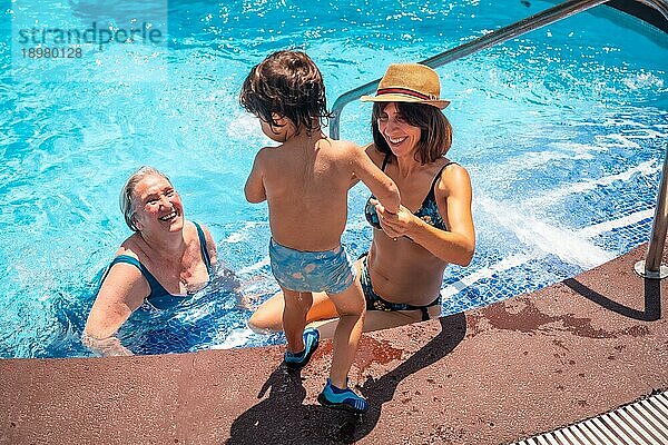 Mutter und Großmutter haben Spaß mit Enkel im Schwimmbad im Sommerurlaub  genießen das Wasser