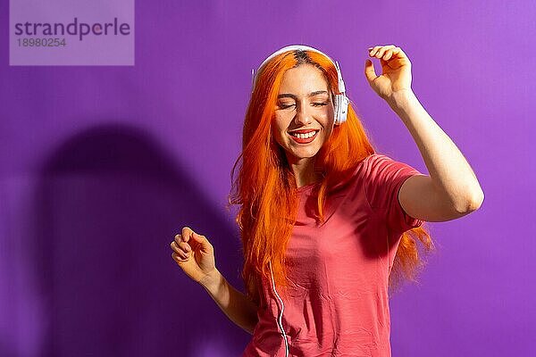 Rothaarige Frau im Studio Fotografie tanzen auf einem lila Hintergrund  mit einem harten Licht