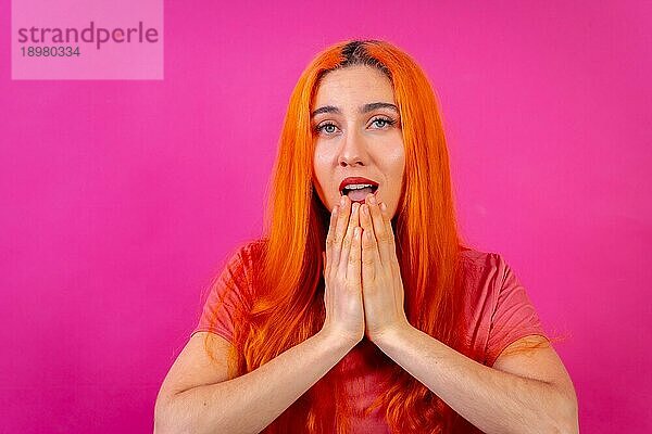 Rothaarige Frau im Studio Fotografie macht die Geste bitte auf einem rosa Hintergrund