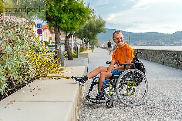 Eine behinderte Person in einem Rollstuhl am Strand im Sommerurlaub