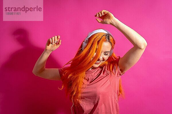 Rothaarige Frau im Studio Fotografie tanzen lächelnd auf einem rosa Hintergrund