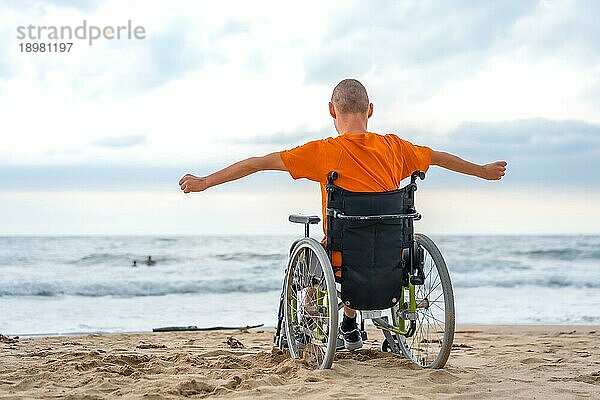 Eine behinderte Person in einem Rollstuhl auf dem Rücken am Strand