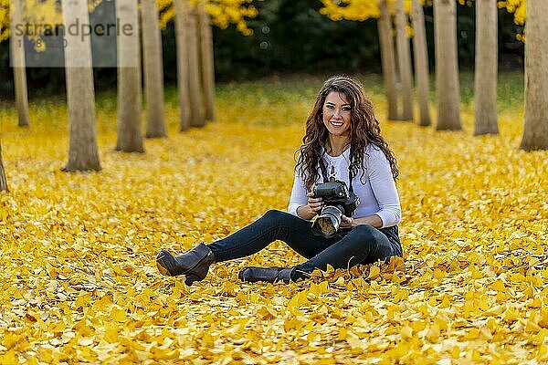 Ein schönes brünettes Modell genießt einen Herbsttag mit gelbem Herbstlaub