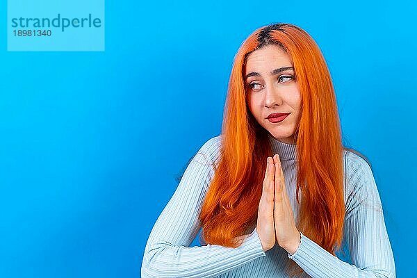 Rothaarige Frau im Studio Fotografie macht die Geste bitte auf einem blauen Hintergrund