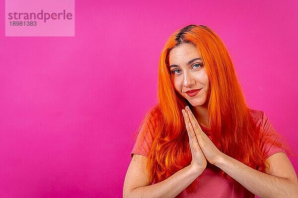 Rothaarige Frau im Studio Fotografie macht die Geste bitte auf einem rosa Hintergrund