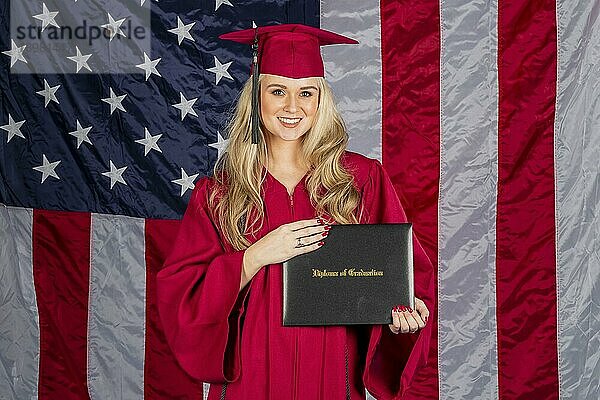 Ein wunderschönes blondes Modell posiert mit einem Diplom mit einer amerikanischen Flagge im Hintergrund