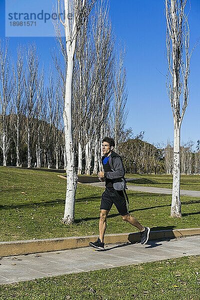 Junger attraktiver Sportler Sportler Läufer joggt am Morgen im öffentlichen Park. Raum kopieren
